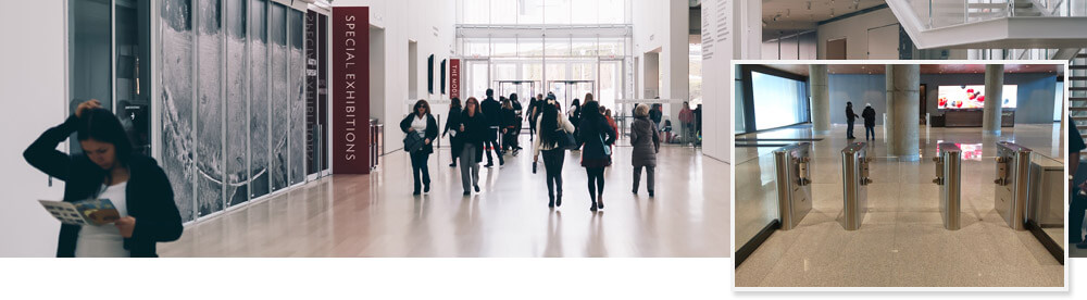 People walking through lobby of museum with turnstiles